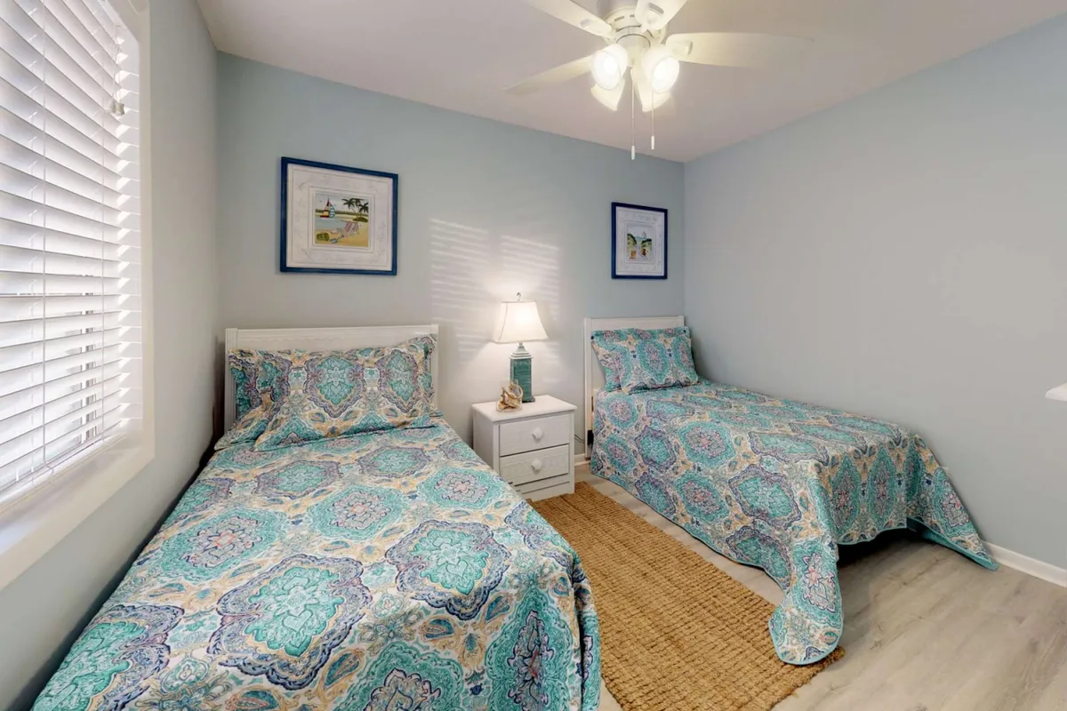 A cozy bedroom with intricately patterned bedding, a nightstand with a lamp, and wall art. The inviting atmosphere is perfect for children or friends, reflecting a warm and welcoming retreat.