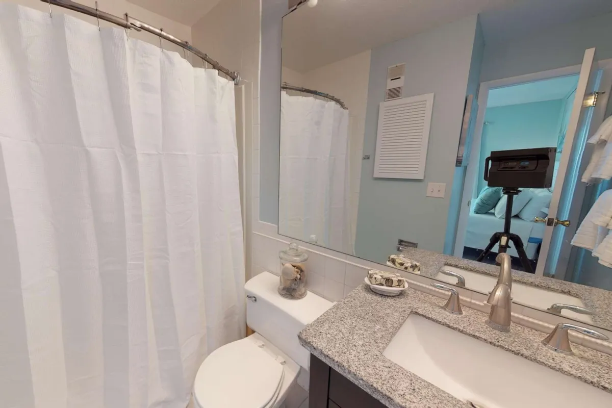 A sparkling bathroom featuring a mirrored vanity, granite countertop, and a white shower curtain. The space is bright, clean, and designed for relaxation and convenience.