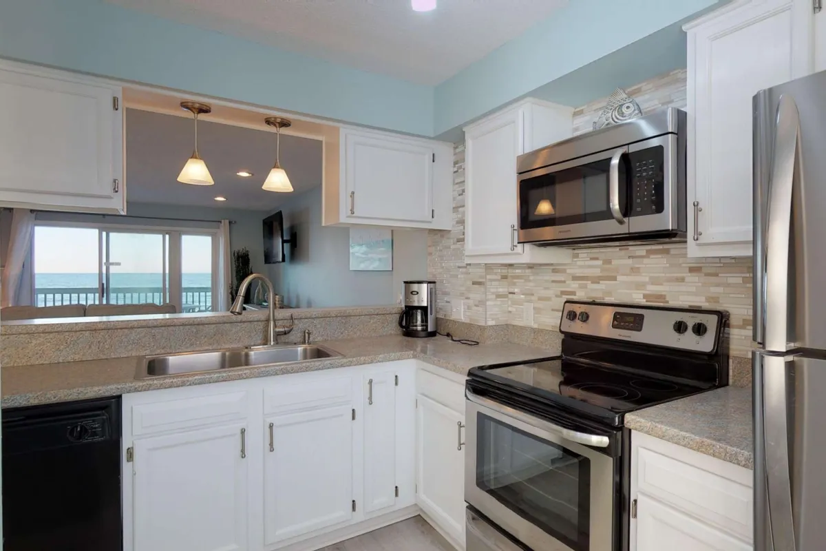 This image features a welcoming kitchen space with a prominent countertop, modern appliances, and a window that lets in ample natural light. The scene conveys a functional yet inviting atmosphere, perfect for cooking or gathering around the kitchen area.