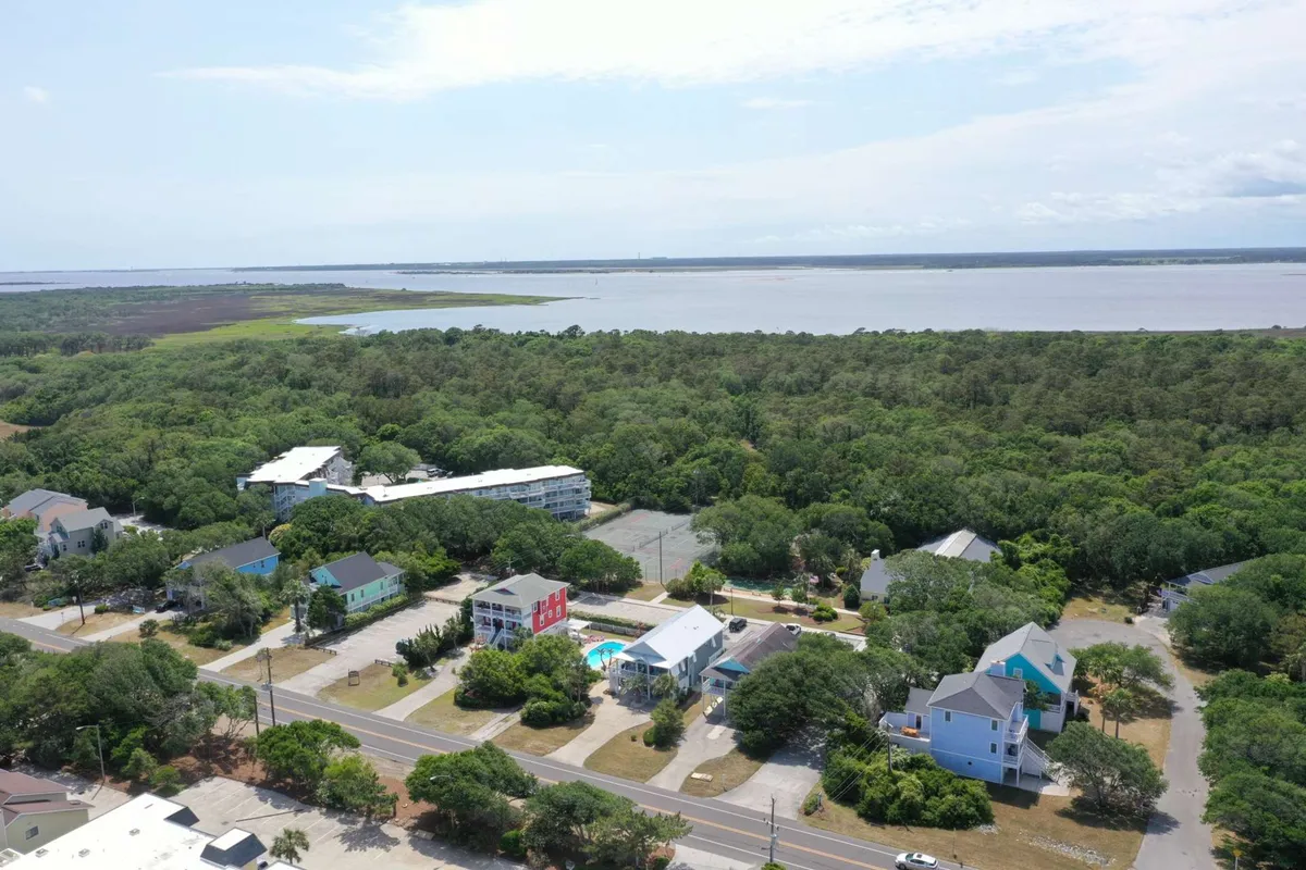 A scenic view of the Ocean Dunes community, highlighting lush greenery, waterfront areas, residential buildings, and a sparkling swimming pool. The image captures an inviting resort atmosphere and suggests various on-site activities like swimming, nature walks, and family gatherings.